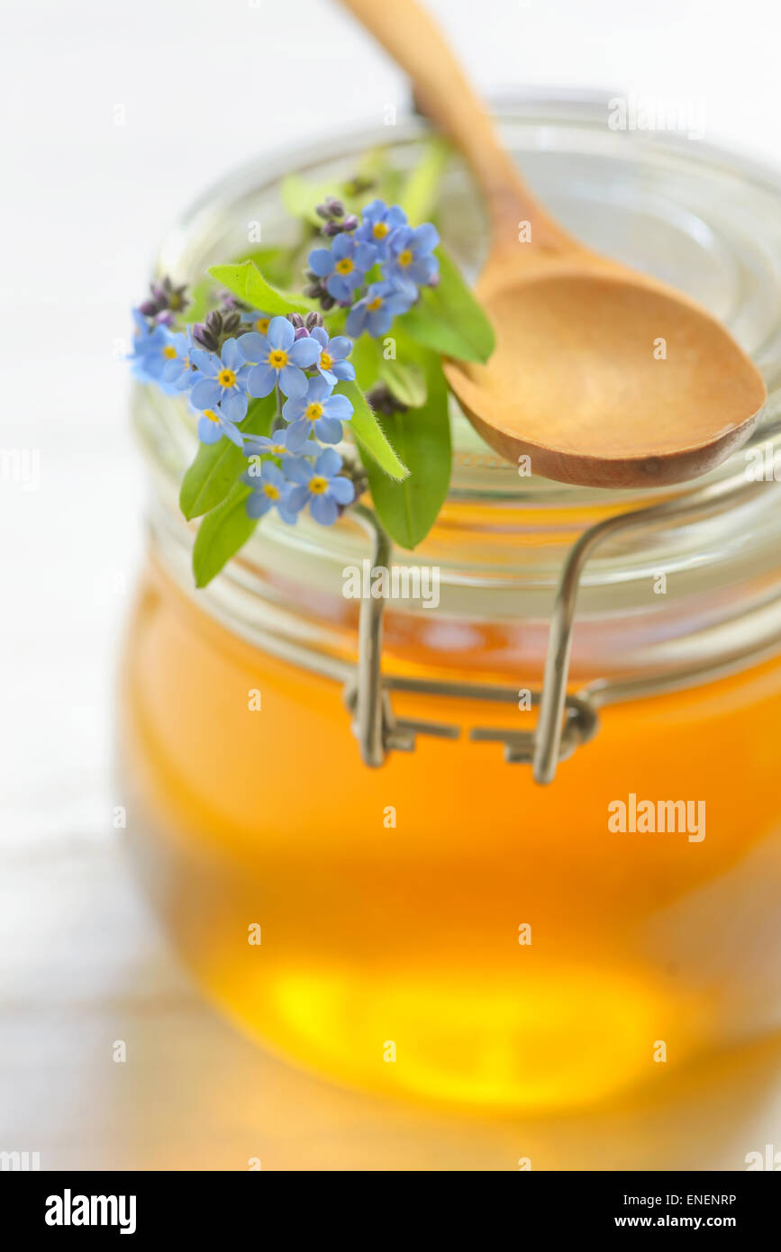 Il vasetto di vetro pieno di miele e il cucchiaio Foto Stock