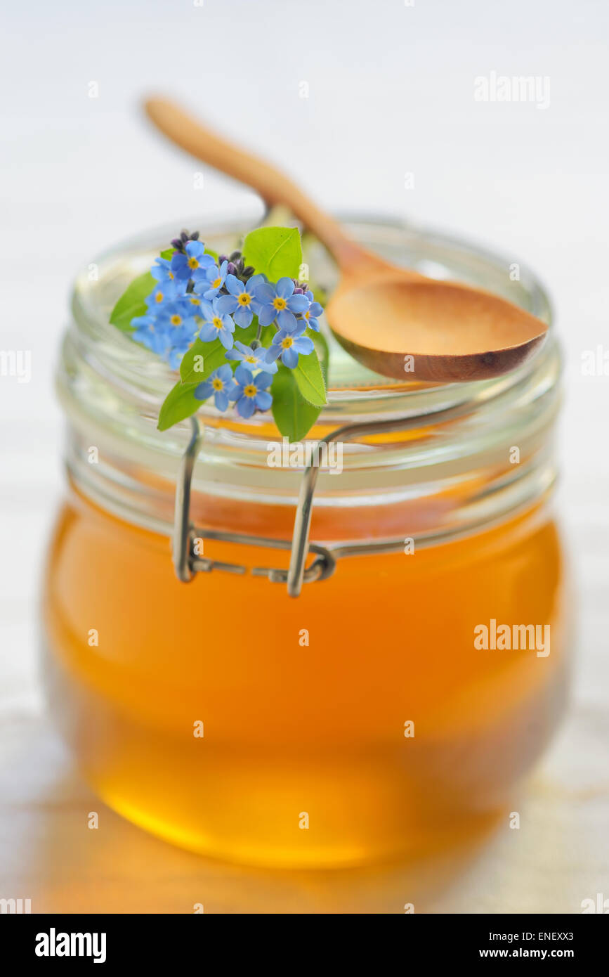 Il vasetto di vetro pieno di miele e il cucchiaio Foto Stock