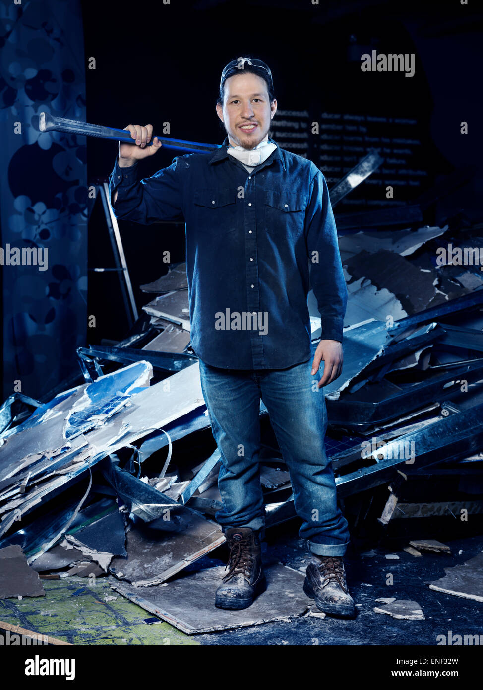 Ritratto di un uomo lavoratore edile, con una mazza in piedi da un cumulo di macerie da demolizione Foto Stock