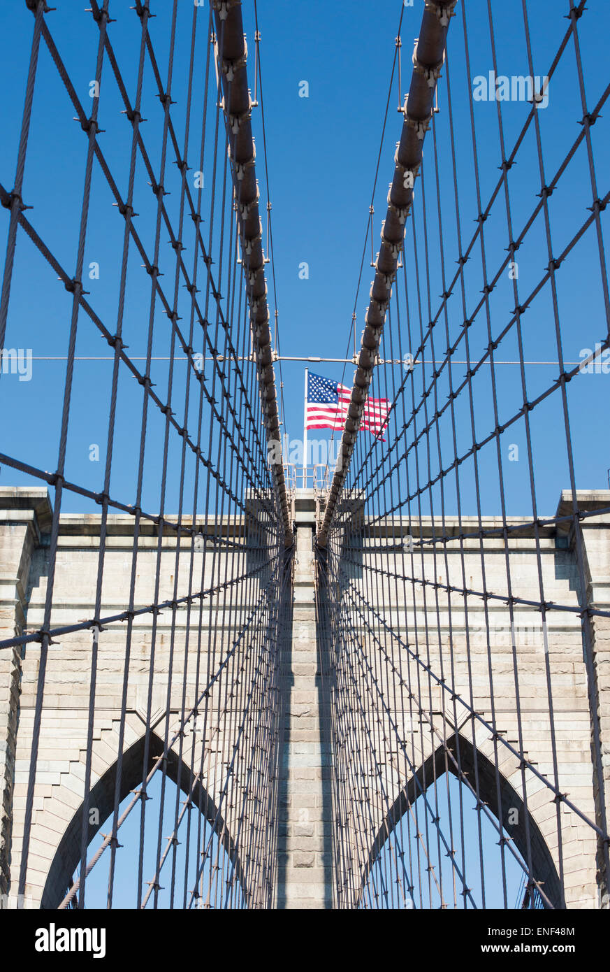 New York, nello Stato di New York, Stati Uniti d'America. Ponte di Brooklyn con la bandiera americana volare sopra i cavi e distinti Foto Stock