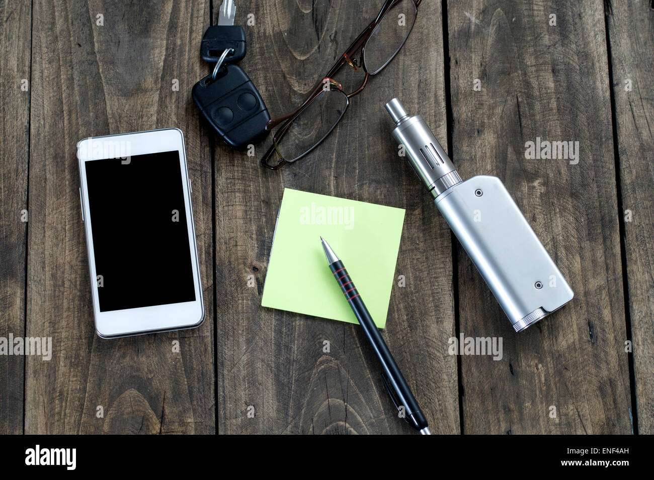 Gli uomini di accessori , vista dall'alto su un sfondo di legno, contiene il telefono , key, penna, bicchieri e e-sigaretta Foto Stock