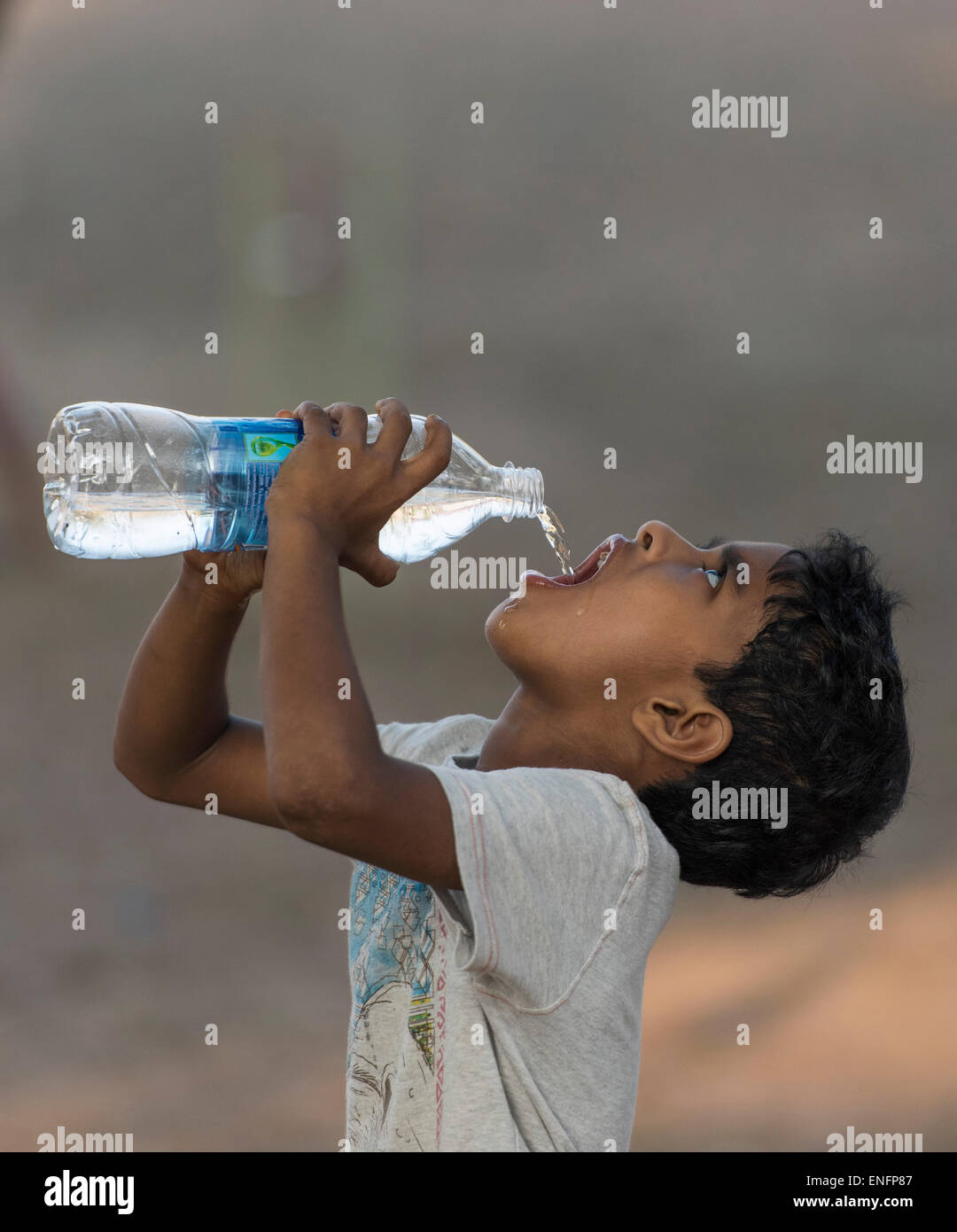 Ragazzo acqua potabile da una bottiglia di plastica, Fort Cochin, Kochi, Kerala, India Foto Stock