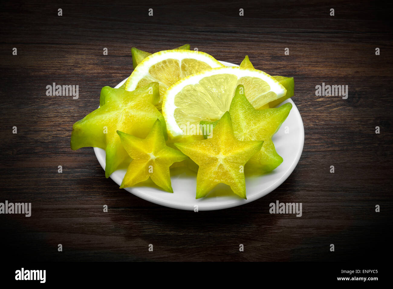 Carambole e limone su legno marrone scuro dello sfondo. Foto Stock