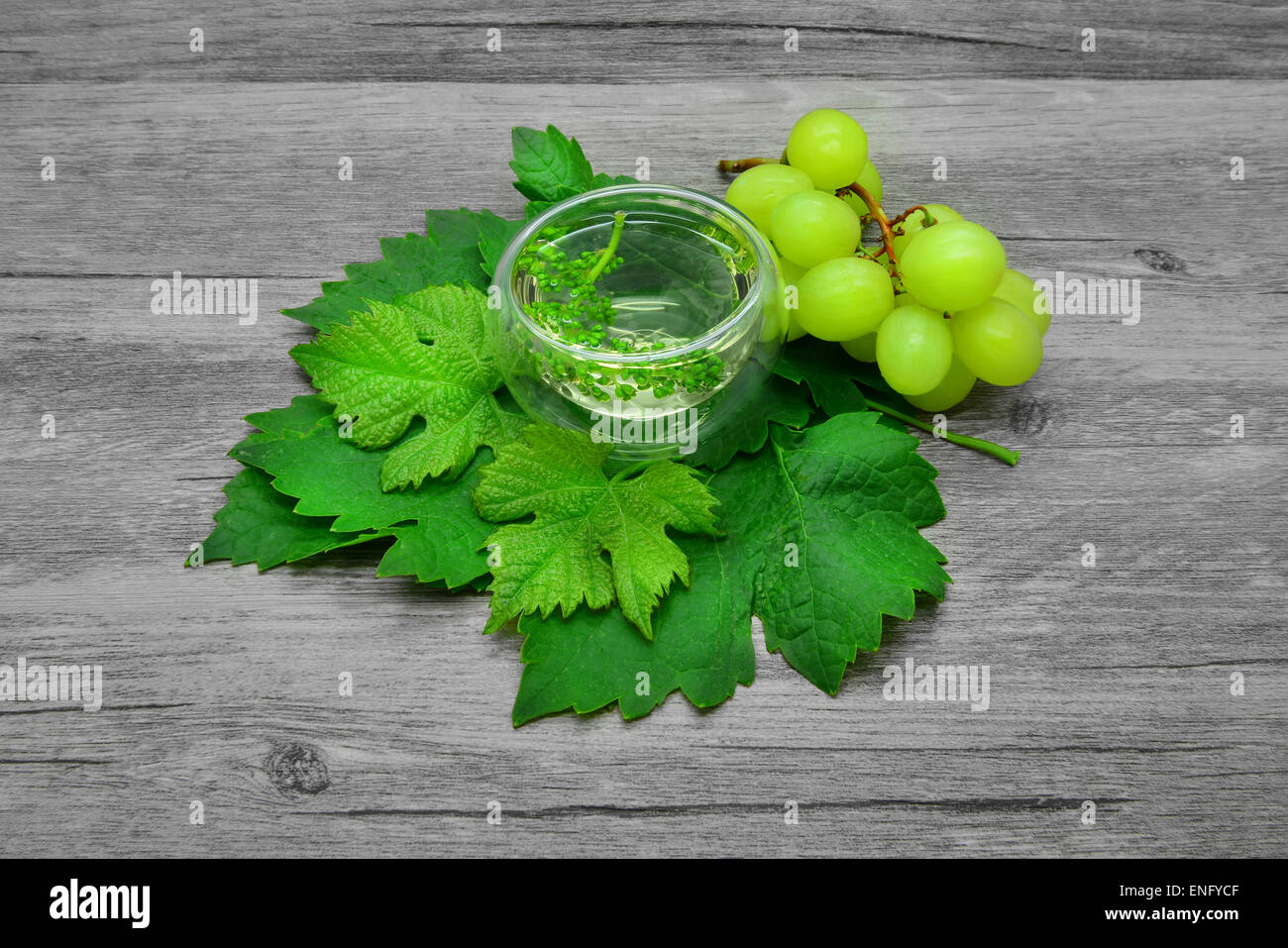 Foglie di uva e di vino bianco su uno sfondo di legno. Foto Stock