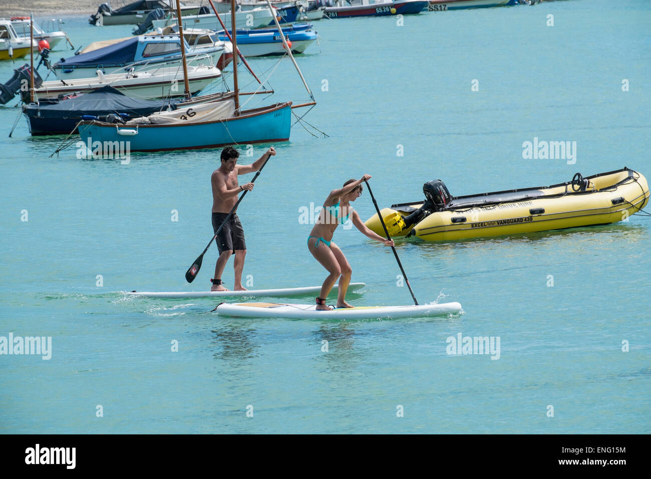 St Ives, Cornovaglia: un paio utilizzando paddle-boards per ottenere attraverso St Ives Harbour Foto Stock