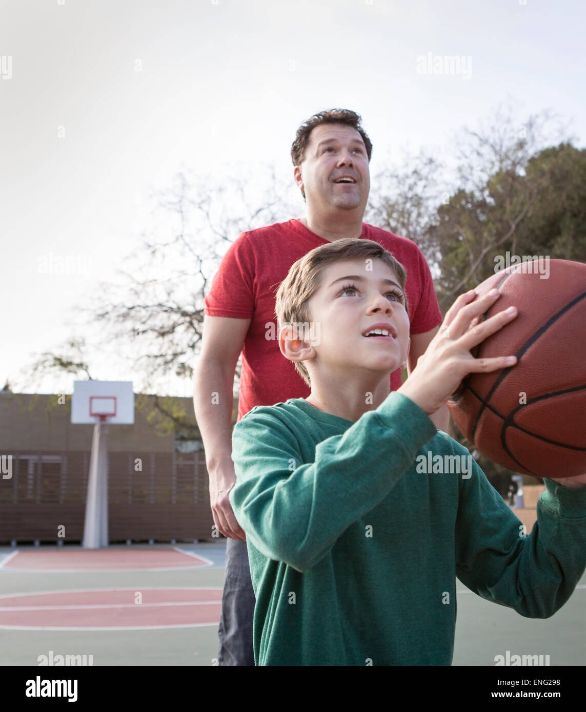 Padre caucasico guardando figlio tenere la pallacanestro su corte Foto Stock
