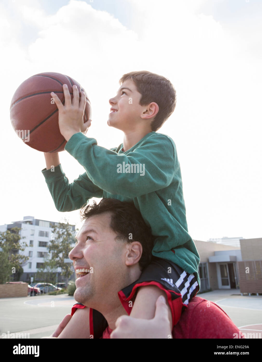Padre caucasici che trasportano il figlio con la pallacanestro su spalle Foto Stock