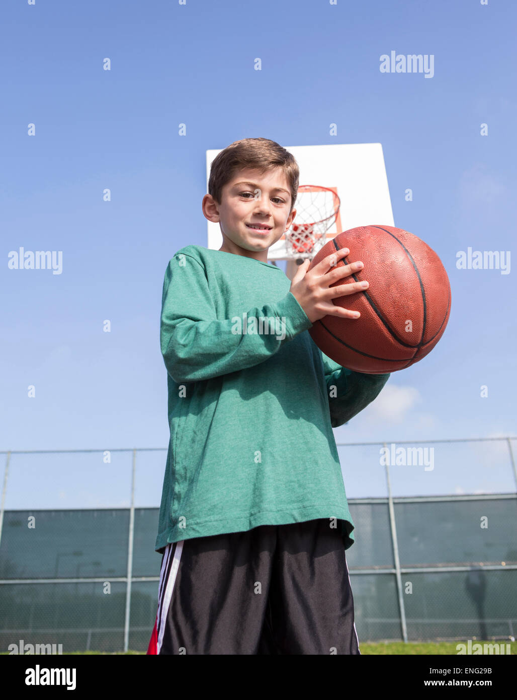 Basso angolo vista del ragazzo caucasico tenendo la pallacanestro su corte Foto Stock