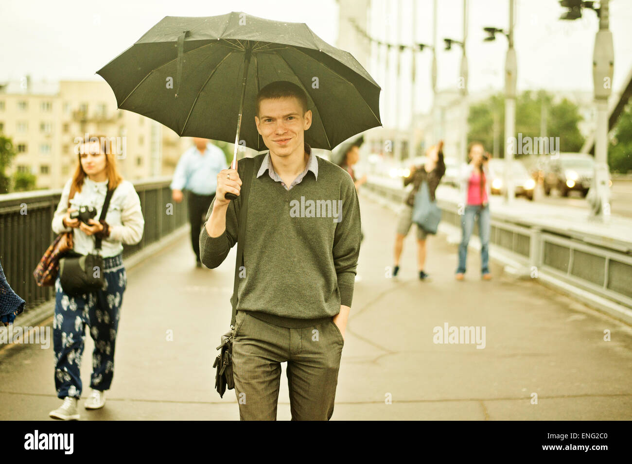 Uomo caucasico camminare sotto ombrello sul marciapiede Foto Stock