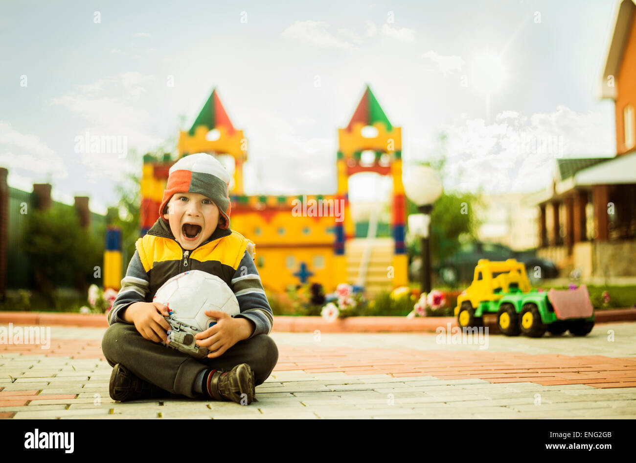 Ragazzo caucasico con bocca aperta tenendo palla al parco giochi Foto Stock