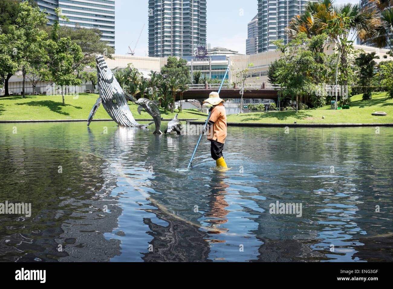 Un lavoratore migrante pulisce uno dei laghi del Parco KLCC di Kuala Lumpur in Malesia. Foto Stock