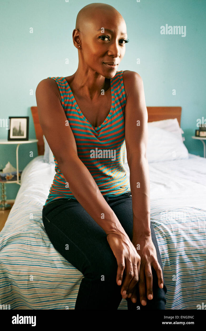 Sorridente americano africano donna seduta sul letto Foto Stock