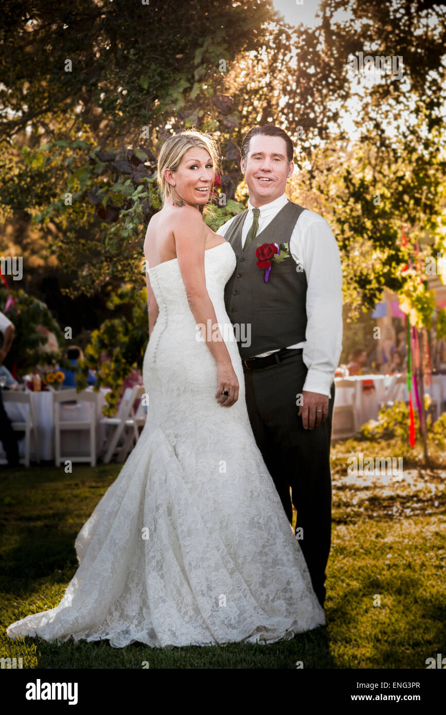 Caucasian sposa e lo sposo sorridente al ricevimento all'aperto Foto Stock