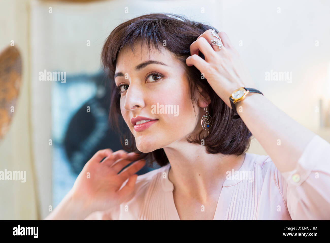 Donna ispanica ammirando i capelli in specchio Foto Stock