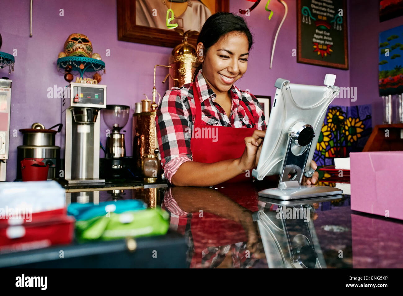 Ispanico barista utilizzando digitale compressa registro nel coffee shop Foto Stock