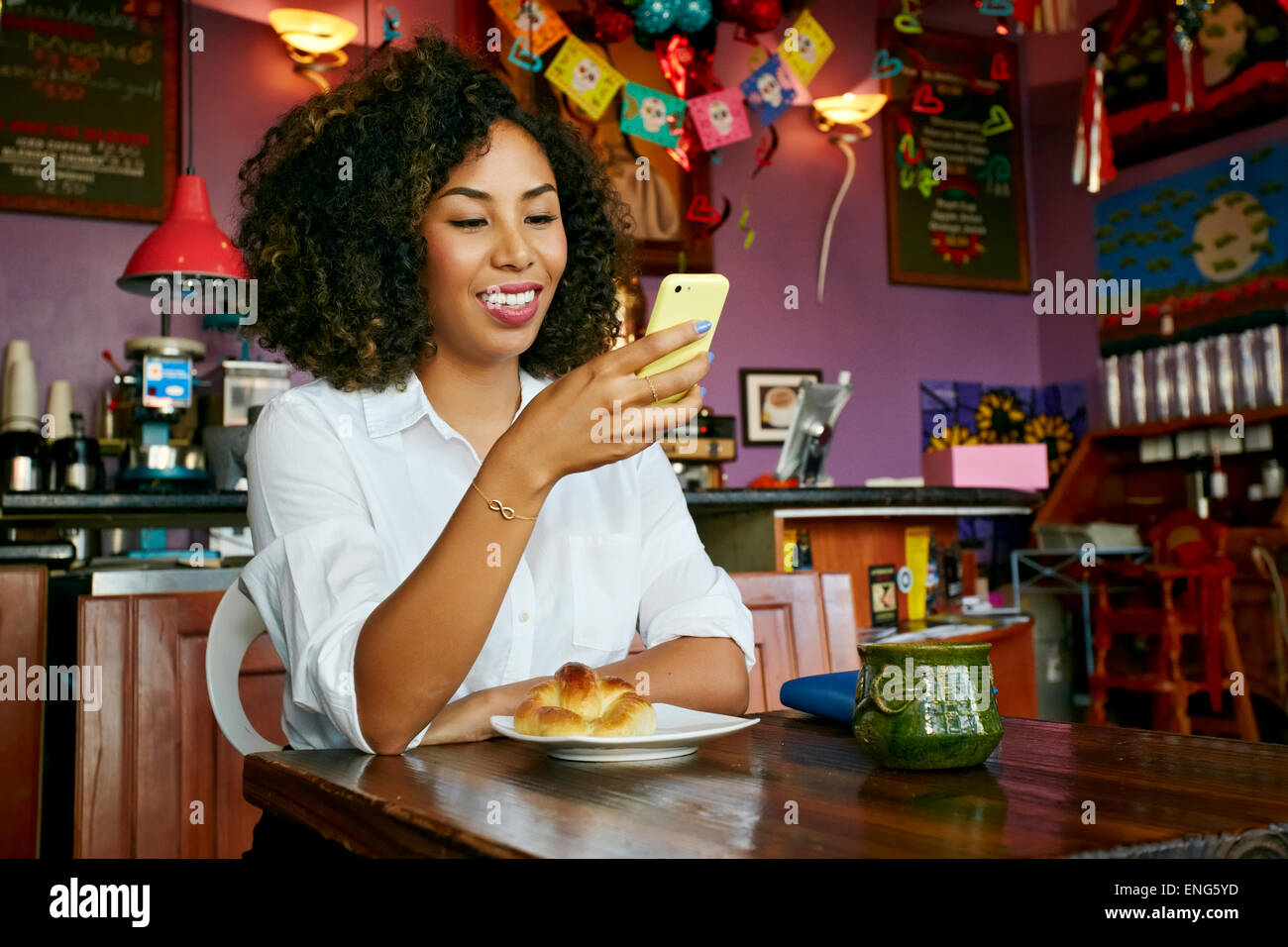 Razza mista donna utilizzando il cellulare in cafe Foto Stock