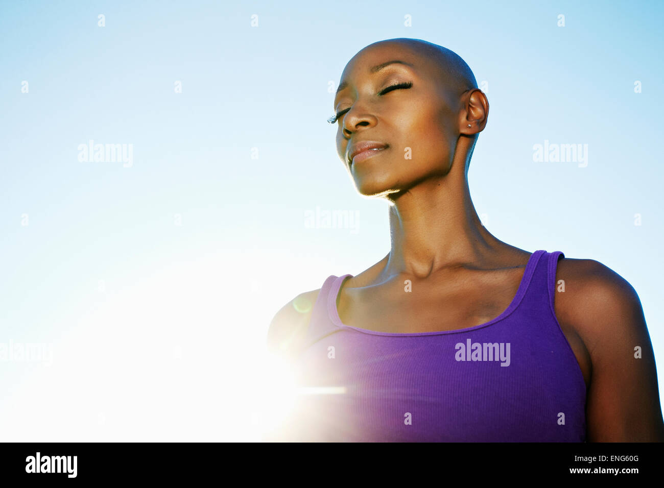 African American donna sorridente in sunburst sotto il cielo blu Foto Stock