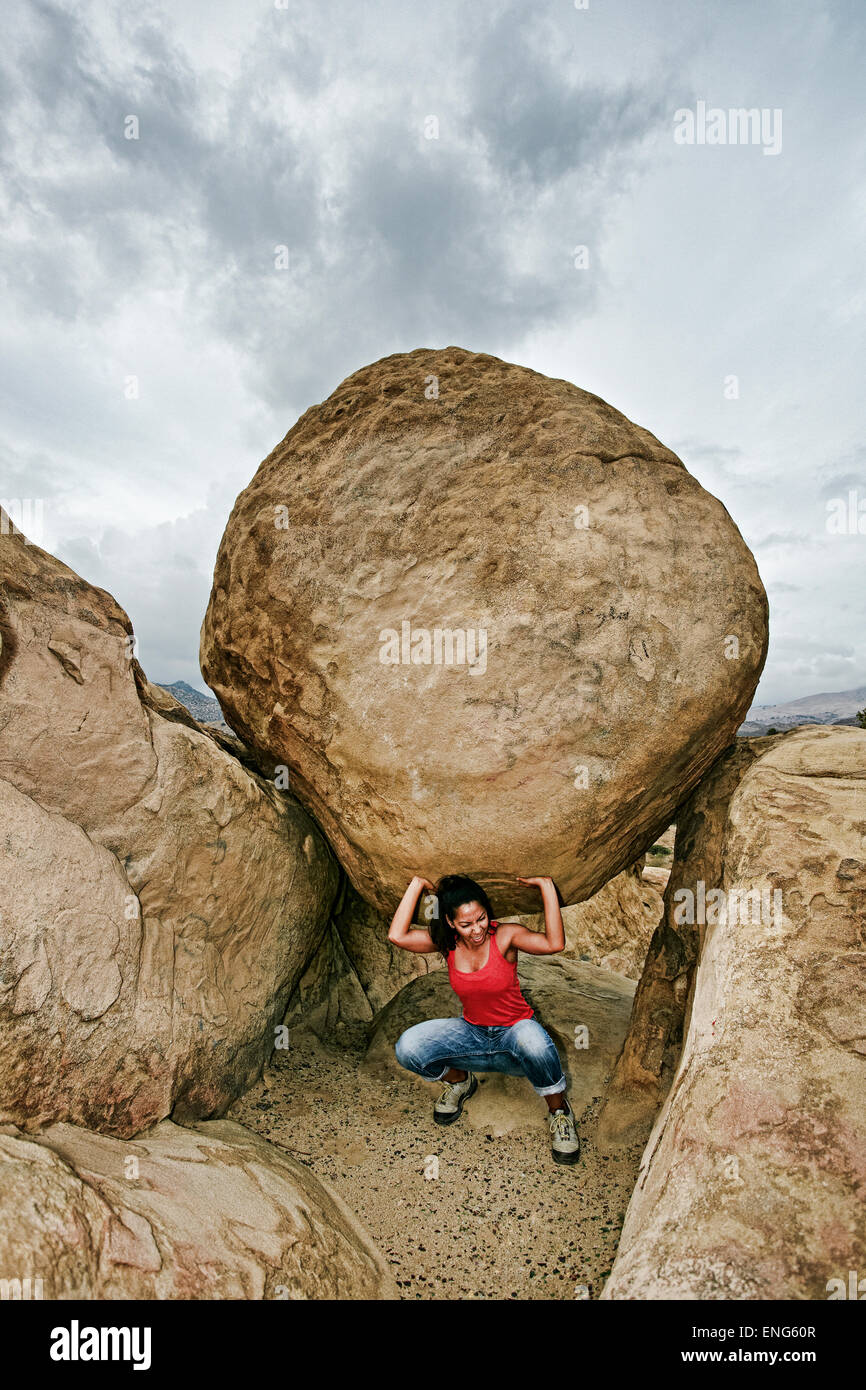 Donna ispanica boulder di sollevamento sulla collina rocciosa Foto Stock