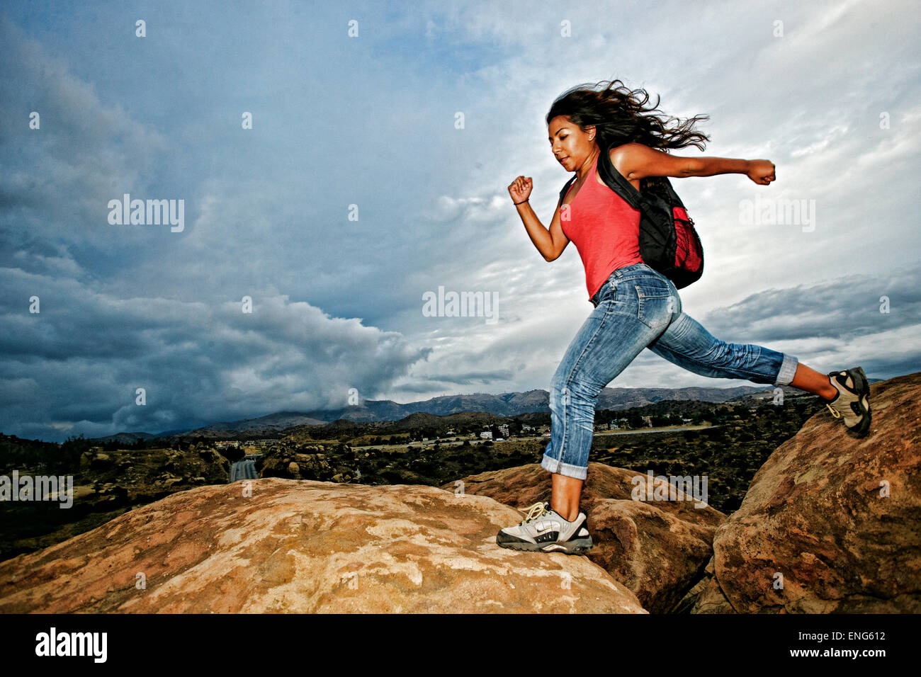 Donna ispanica jumping crepaccio sulla formazione di roccia Foto Stock