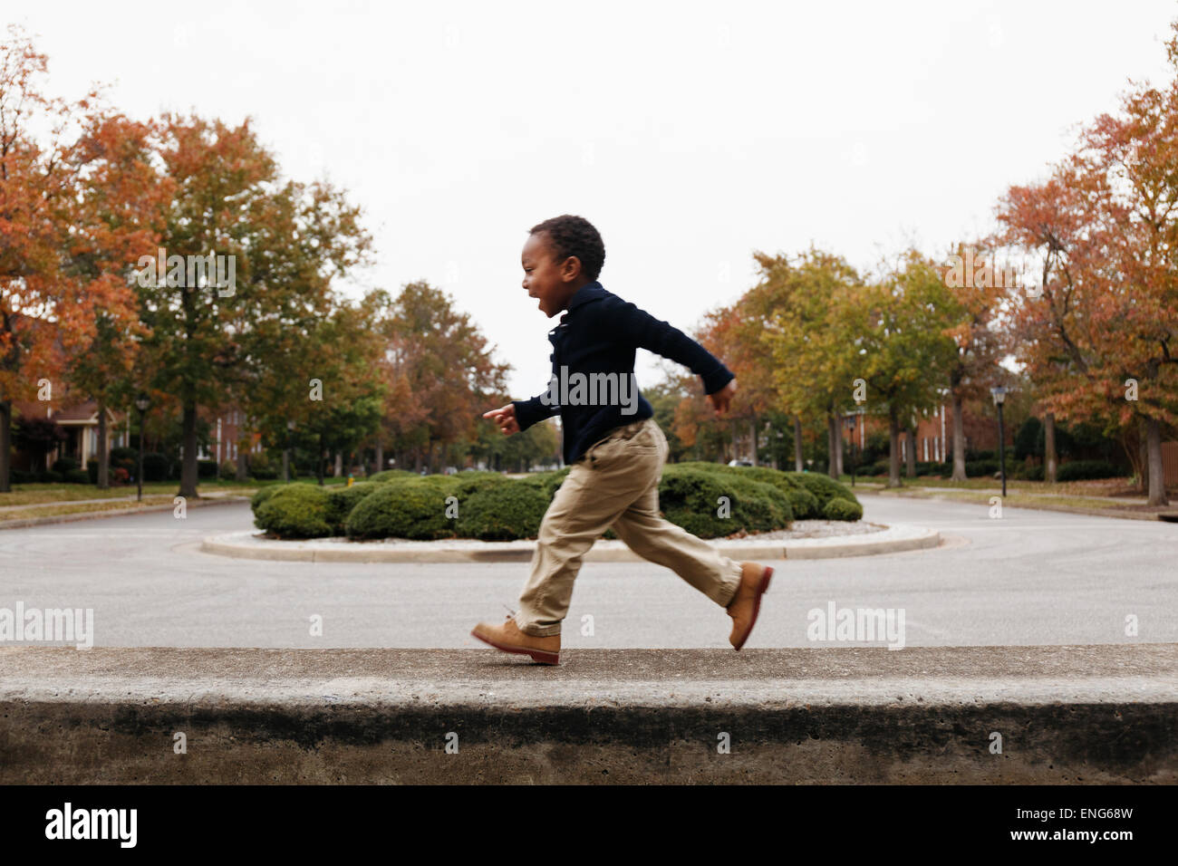 African American boy giocando sulla strada suburbana Foto Stock