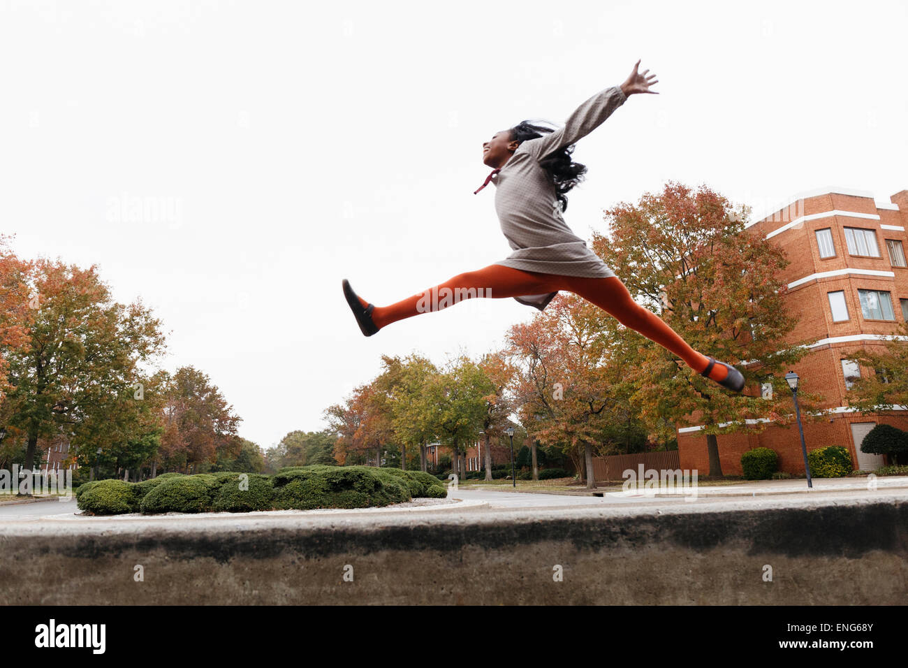 African American Girl salti di gioia sulla strada suburbana Foto Stock