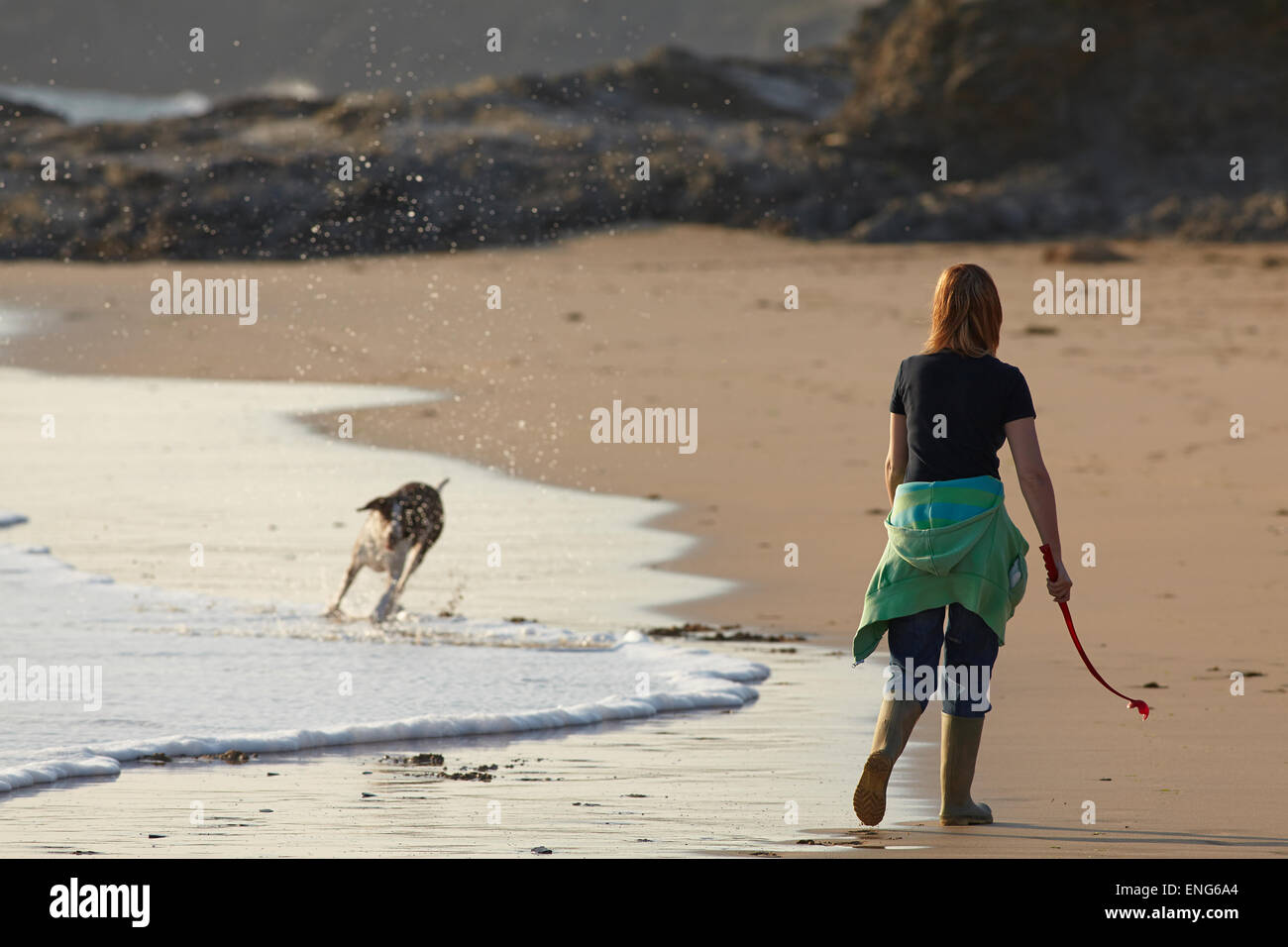 Una donna che cammina il suo cane sulla spiaggia di Constantine Bay, vicino a Padstow, in Cornovaglia, Gran Bretagna. Foto Stock