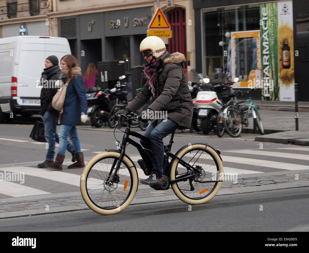 Uomo in sella della bicicletta elettrica indossando il casco del motociclo, Rue Rivoli, Paris, Francia Foto Stock