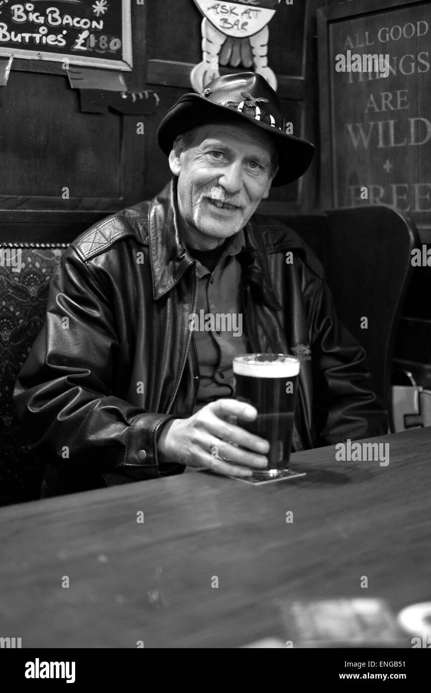 Sorridente uomo vecchio godendo di una pinta di birra nel suo pub locale a Southsea England Regno Unito Foto Stock
