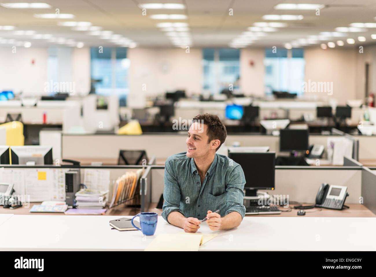 Un giovane uomo seduto ad una scrivania in un ufficio. Foto Stock
