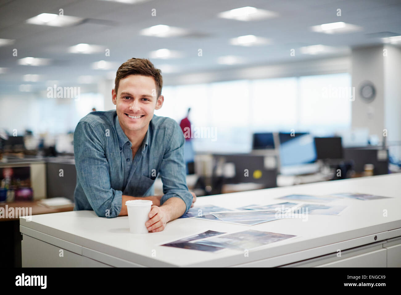 Un uomo sorridente e piegatevi in avanti sulla sua scrivania. Foto Stock