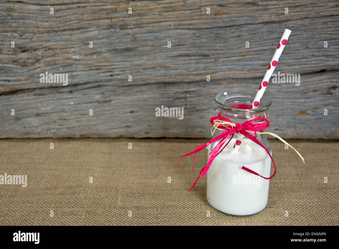 Bianco latte e polka dot paglia in vetro retrò bottiglia di latte su tela. Foto Stock