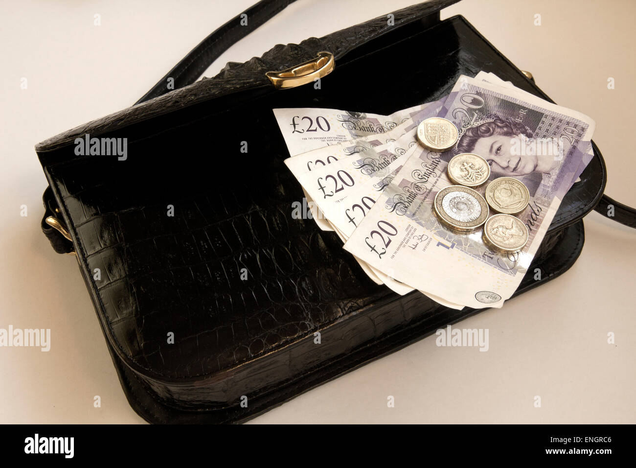 British Pound note£20 e 1 e 2 libbra di monete su nero pelle di coccodrillo borsetta, fermaglio dorato Foto Stock