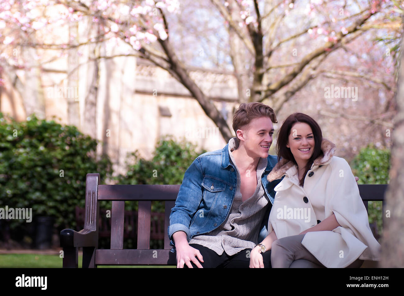 Giovane coppia caucasica in amore seduto su una panchina nel parco Foto Stock
