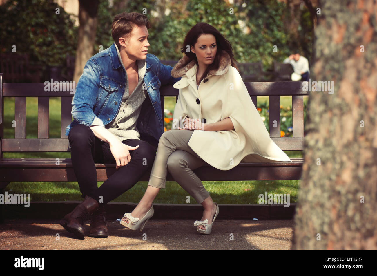 Giovane coppia caucasica in amore seduto su una panchina nel parco Foto Stock