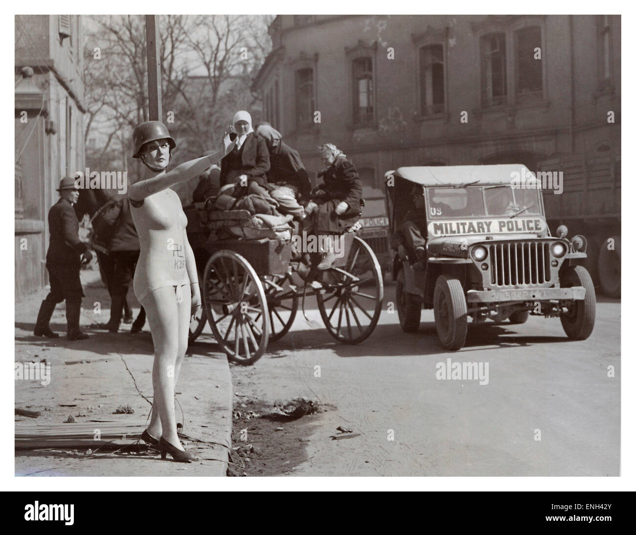 Occupato BERLIN WW2 dark humor immagine nel post guerra 1945 Berlino del negozio helmeted manichino dando Hitler salutate con American jeep e rifugiati dietro Foto Stock