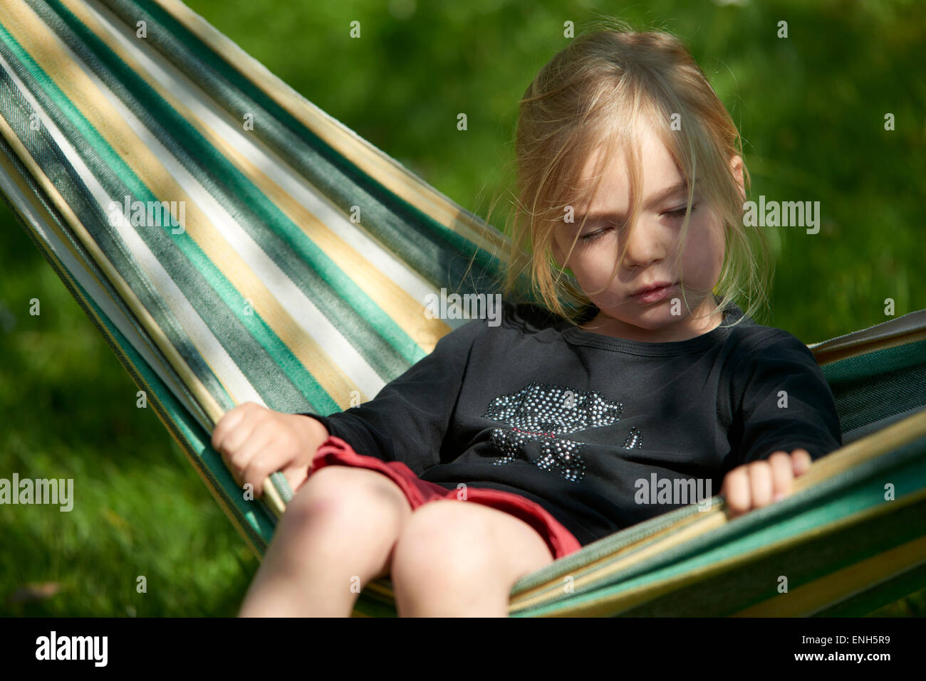 Ritratto di bambino ragazza bionda giacenti e di riposo in una amaca, il giardino, estate Foto Stock