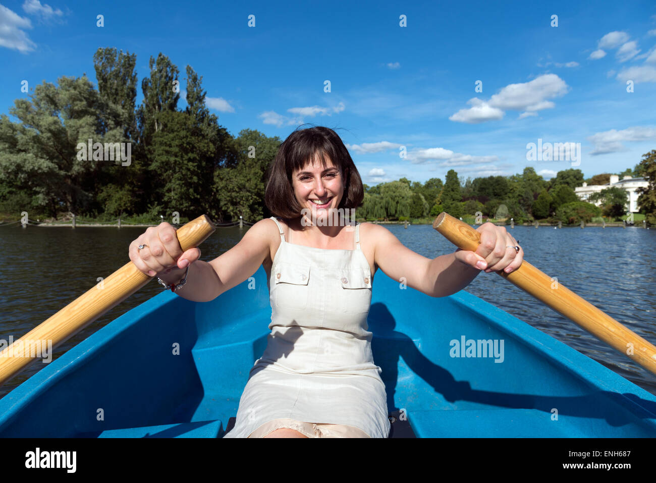 Giovane donna remare una barca sul lago in barca a Regent's Park, London, England, Regno Unito Foto Stock