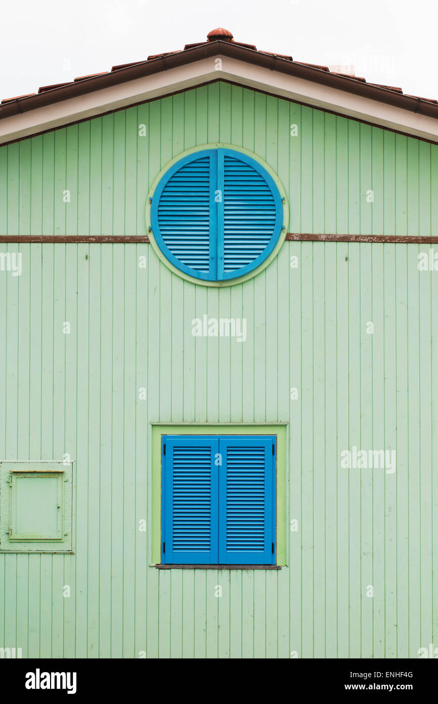 Casa in legno verniciati in verde con circolare e quadrato blu di Windows Foto Stock