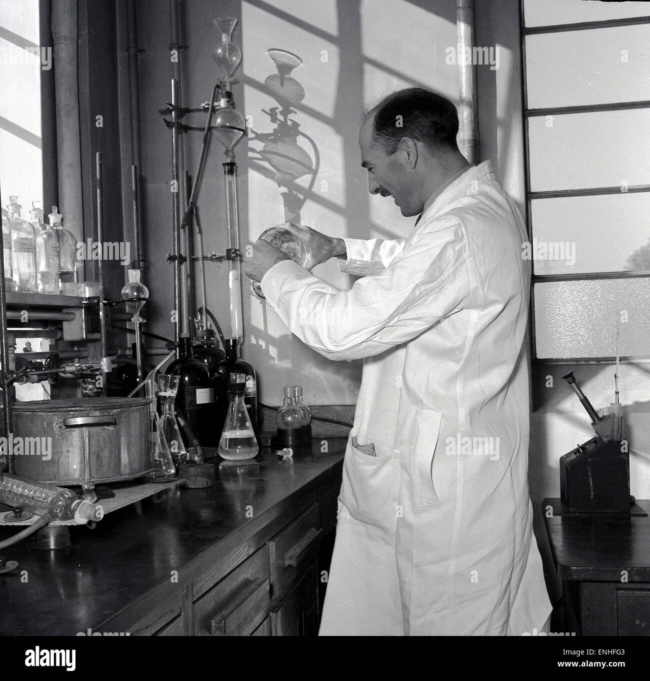 Degli anni Cinquanta, storico, Inghilterra, maschio scienziato in camice bianco nel laboratorio di ricerca lavorando su nuovi farmaci o vaccini. Foto Stock