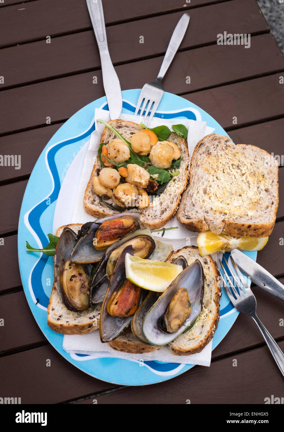 Capesante alla griglia e verde cozze a labbro sul pane in un cibo all'aperto shack sulla spiaggia di Kaikoura, Nuova Zelanda Foto Stock
