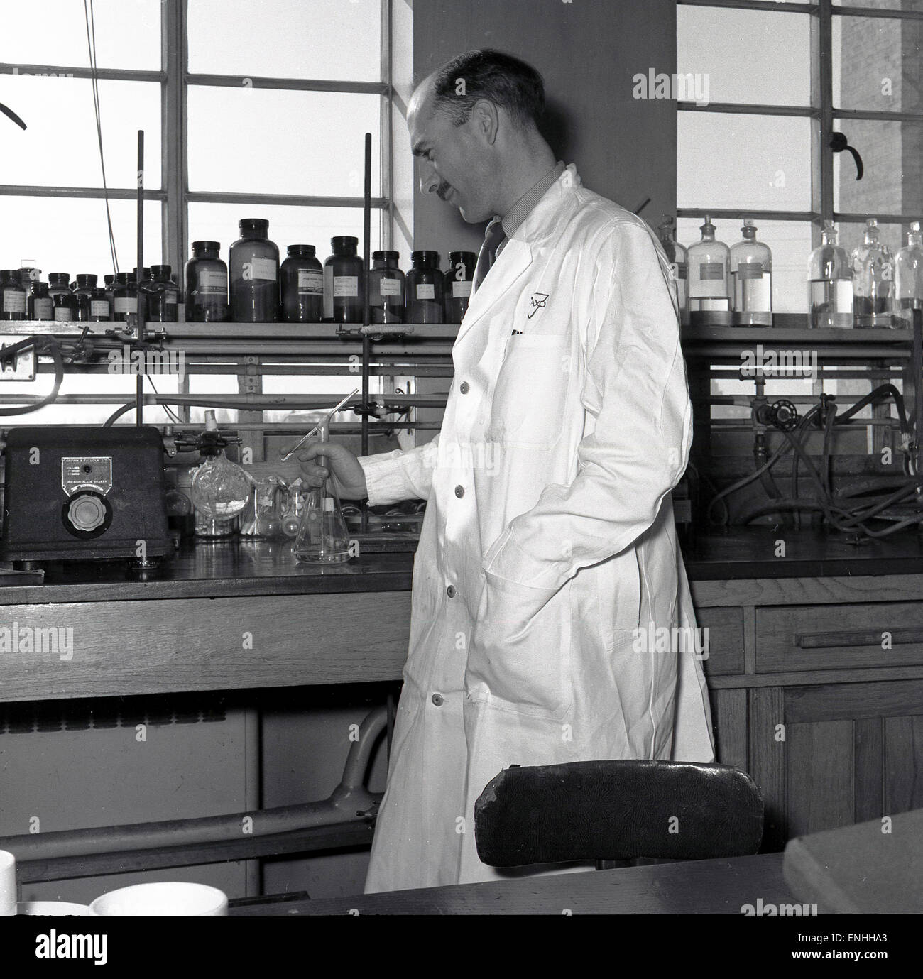 Degli anni Cinquanta, storico, Inghilterra, maschio scienziato in tute bianche in un laboratorio di ricerca. Foto Stock