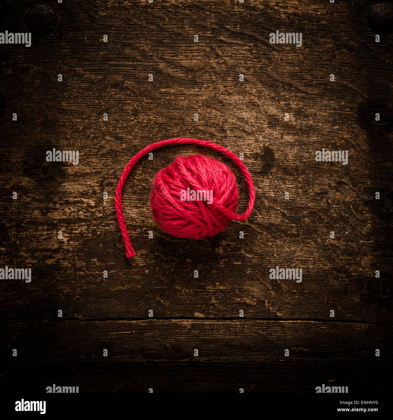 Ancora la vita della sfera del filo rosso sul tavolo di legno. Immagine concettuale di tessitura a maglia o a crochet. Foto Stock