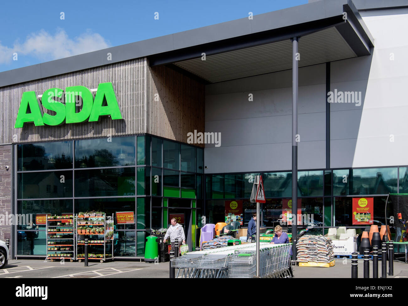 Supermercato Asda ingresso del negozio con carrelli nel parcheggio auto al di fuori del negozio di fronte. Bangor, Gwynedd, Wales, Regno Unito, Gran Bretagna Foto Stock
