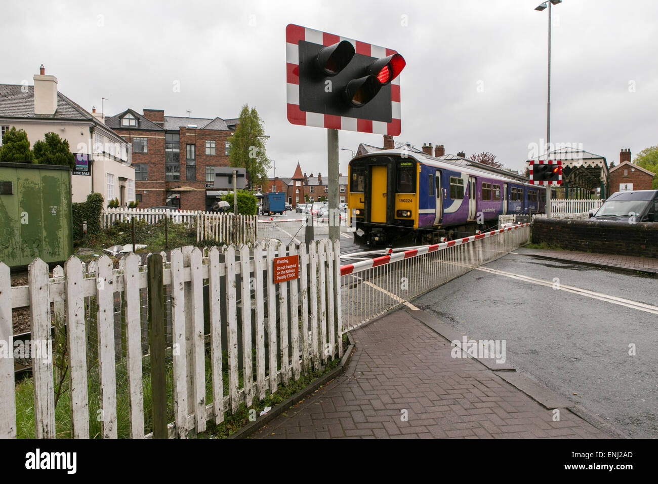 A nord del convoglio ferroviario passa attraverso un passaggio a livello a Hale , Greater Manchester Foto Stock