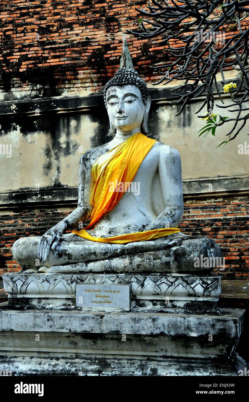 Ayytthaya, Thailandia: grande pietra scolpita Buddha seduto alla base del grande mattone Chedi di Wat Yai Chai Mongkon Foto Stock