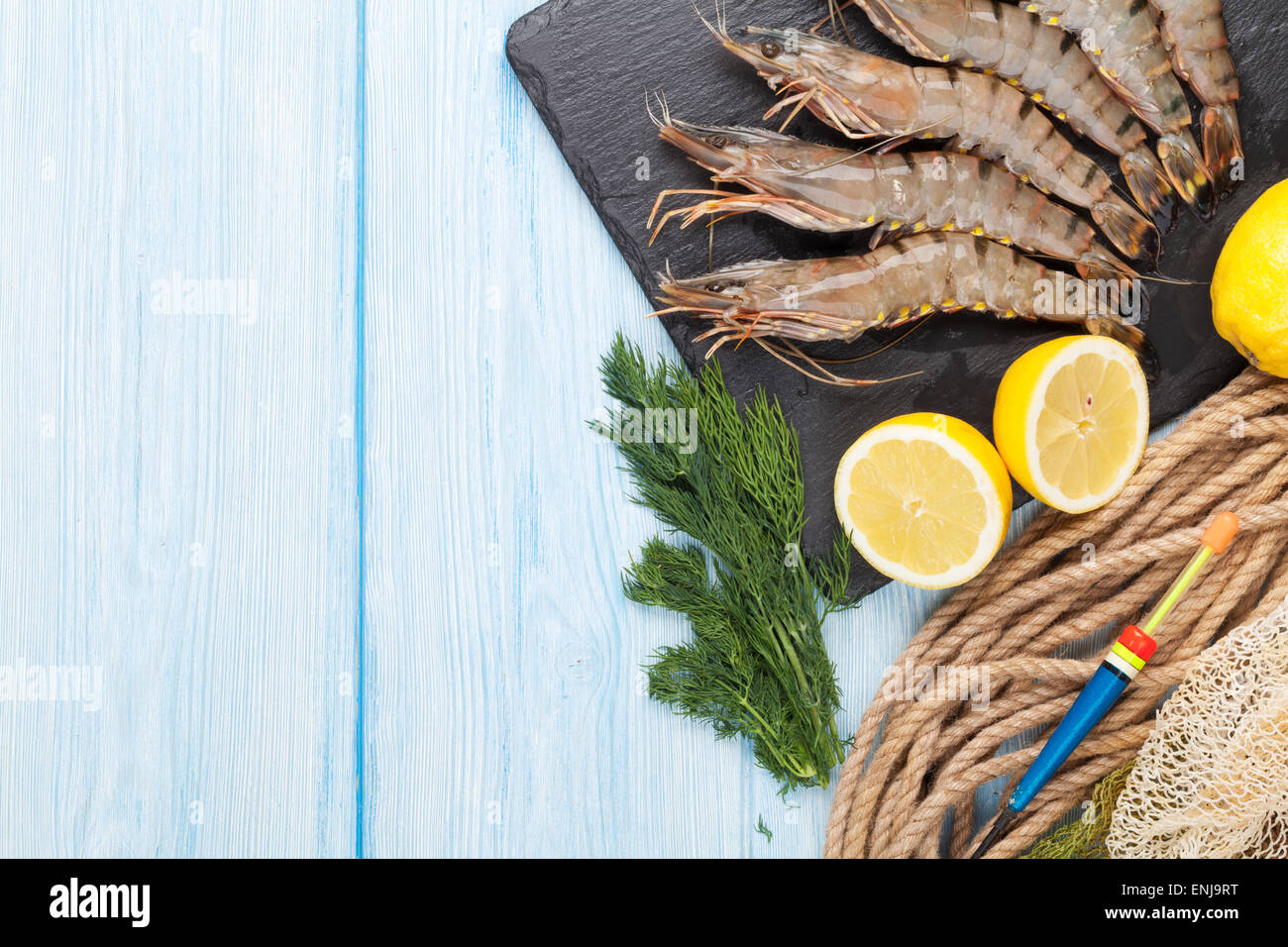 Crudo fresco gamberoni e attrezzature per la pesca su un tavolo di legno. Vista da sopra con lo spazio di copia Foto Stock
