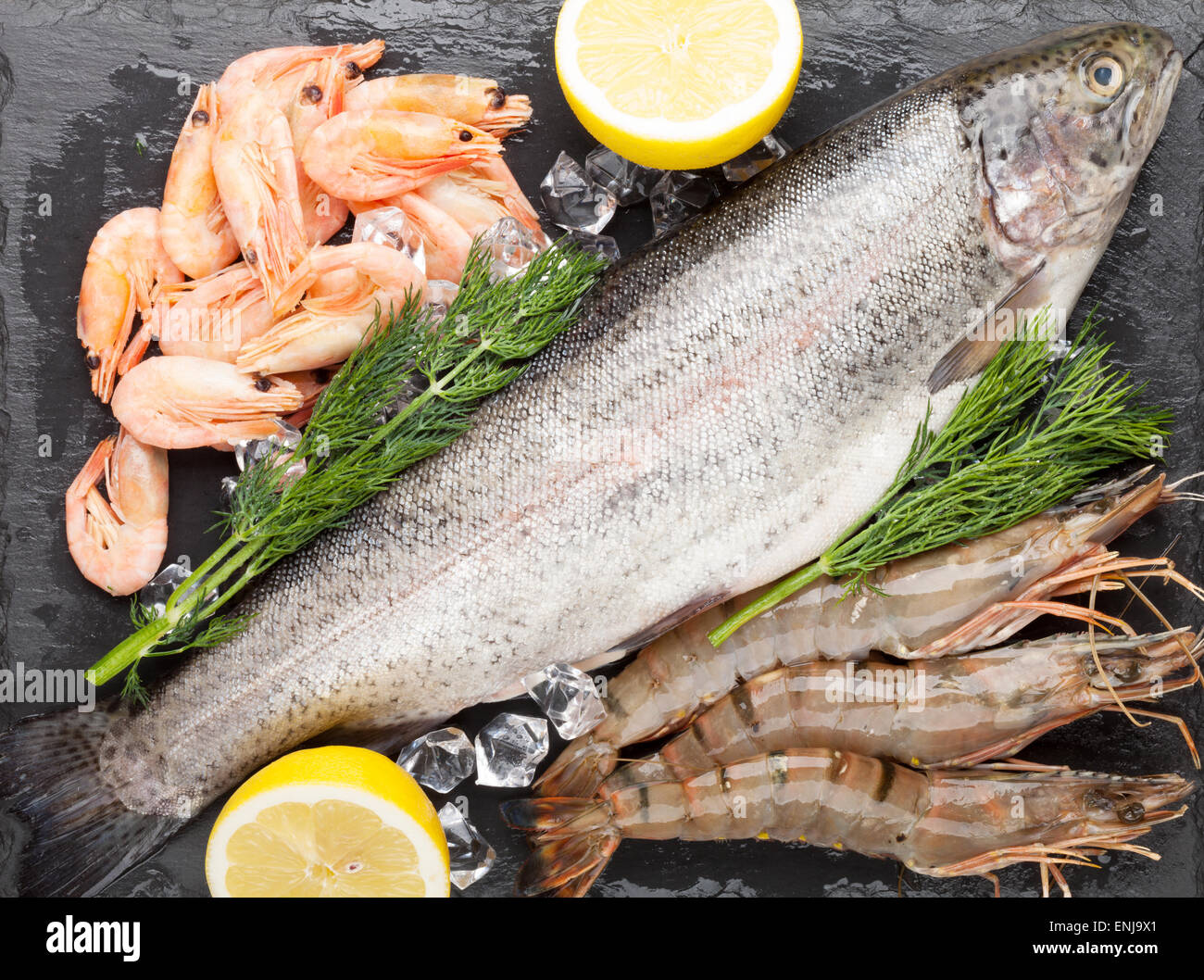 Crudo fresco il cibo del mare con spezie sulla pietra nera dello sfondo. Vista superiore Foto Stock