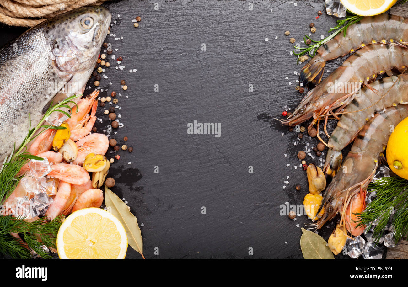 Crudo fresco il cibo del mare con spezie sulla pietra nera dello sfondo. Vista da sopra con lo spazio di copia Foto Stock