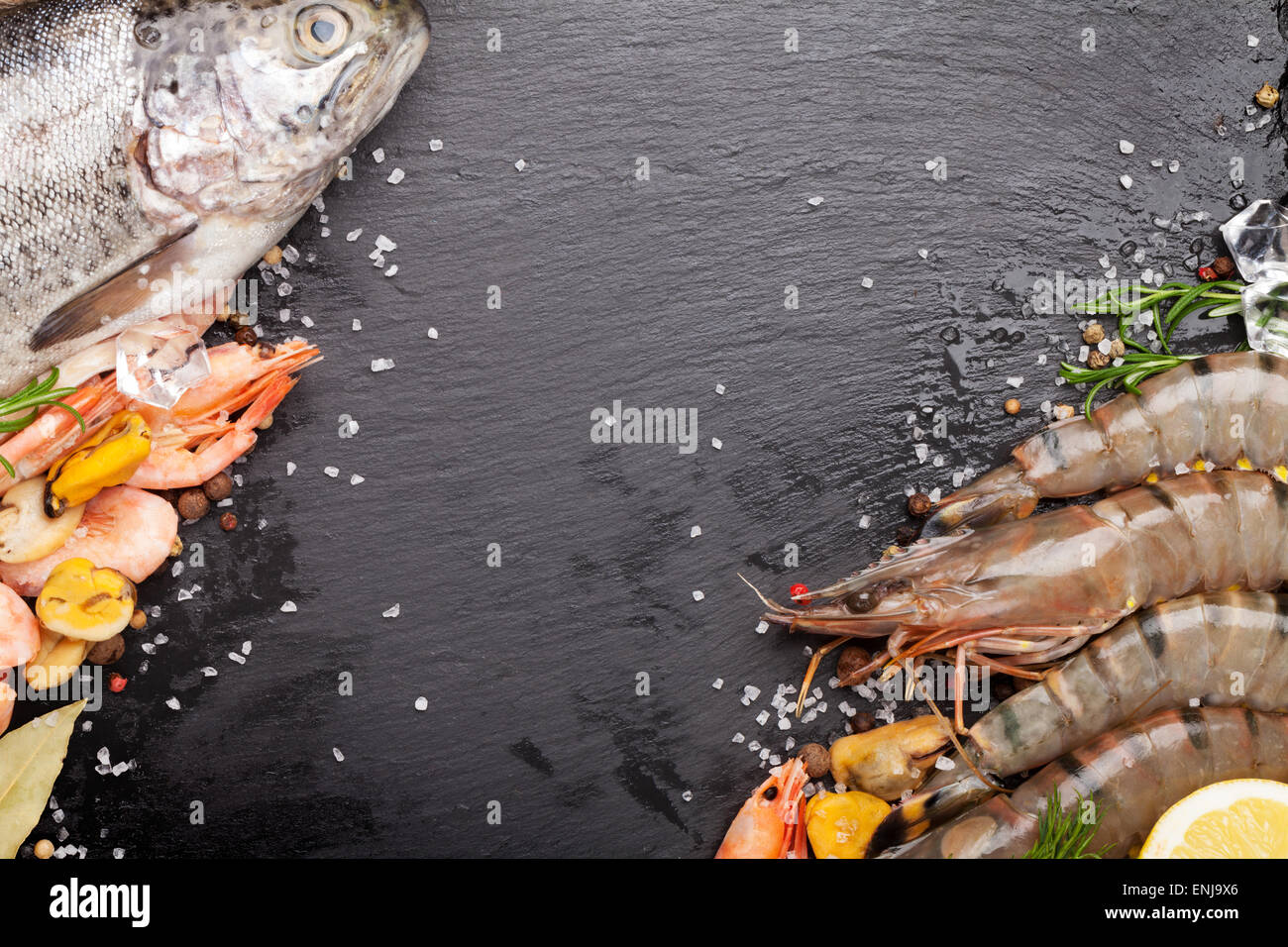 Crudo fresco il cibo del mare con spezie sulla pietra nera dello sfondo. Vista da sopra con lo spazio di copia Foto Stock