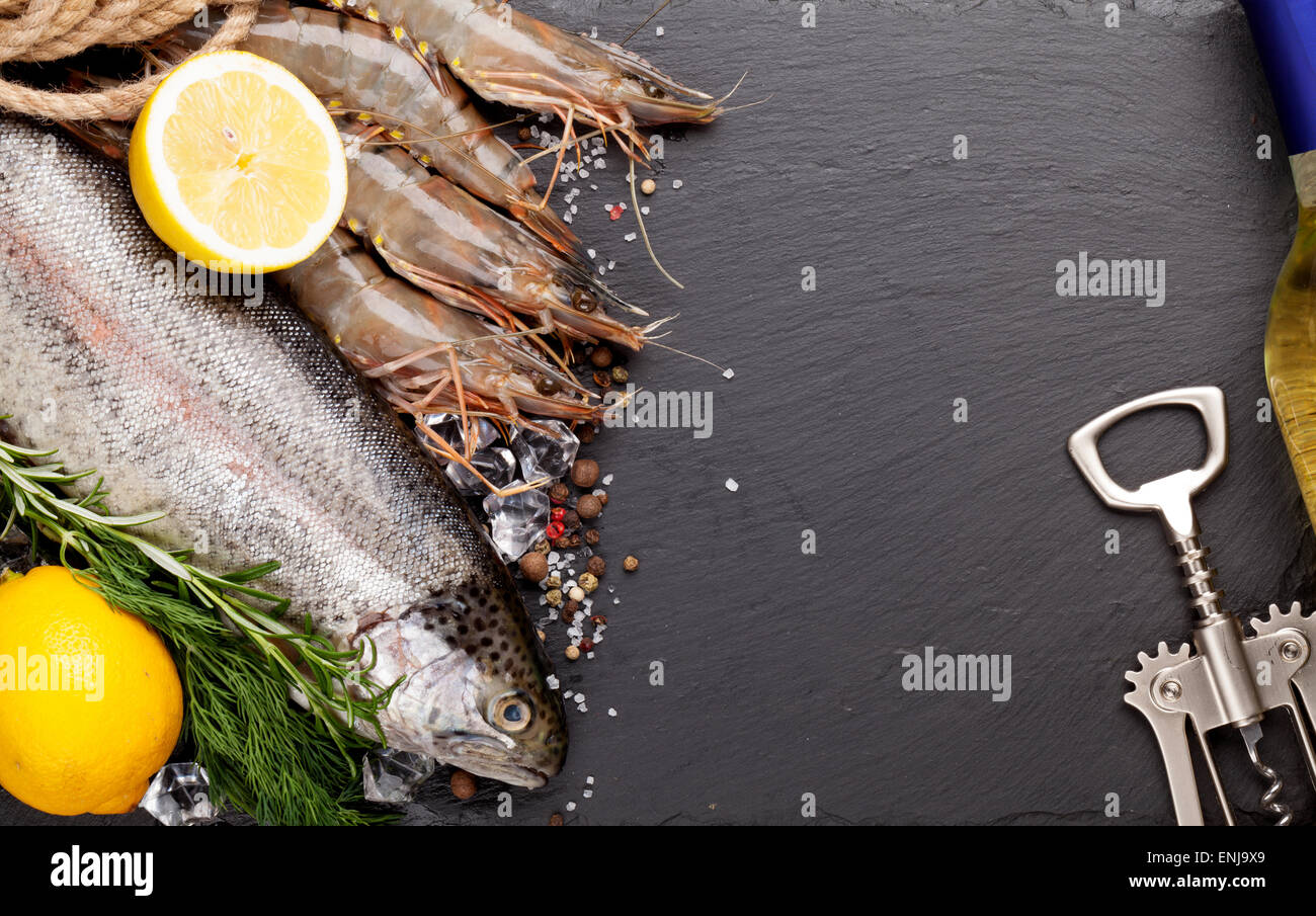 Crudo fresco il cibo del mare con spezie e vino bianco bottiglia su pietra nera dello sfondo. Vista da sopra con lo spazio di copia Foto Stock